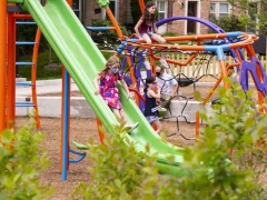 Full color photo of children playing on play equipment at Big Chimneys Park