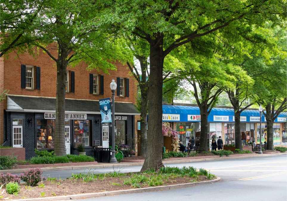 Full color photo of the Tree-line Broad Street with a variety of shops and people milling around.