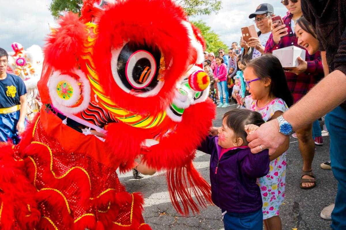 Full color photo of Crowds at the Eden Center during the Dragon Festival with two kids meeting a dragon.