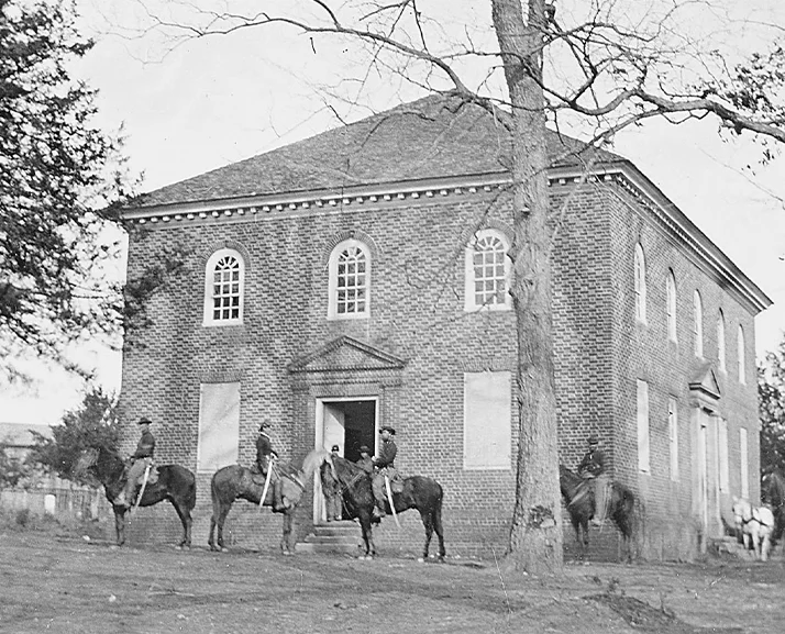 home-history Historical Black and white photo of The Falls Church with people on horses in front of the church.